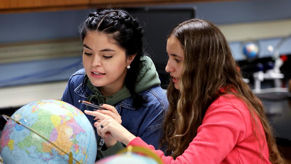 Two students studying a globe in a geosciences class